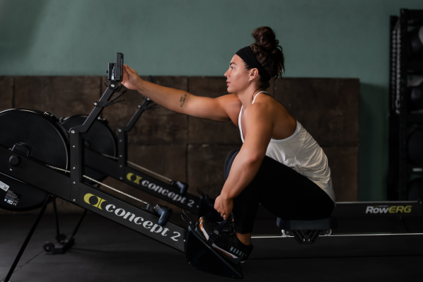 Woman on RowErg pressing PM5 buttons