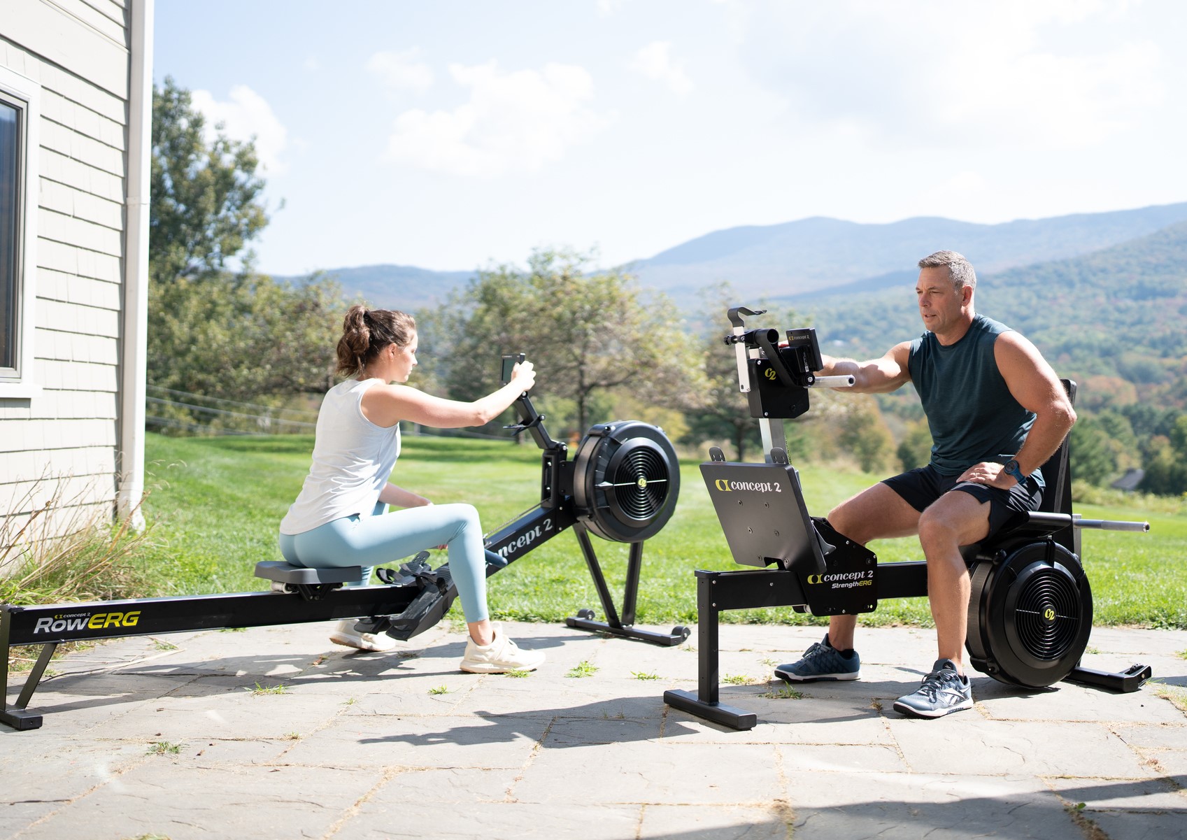man and woman on rowerg and strengtherg outside